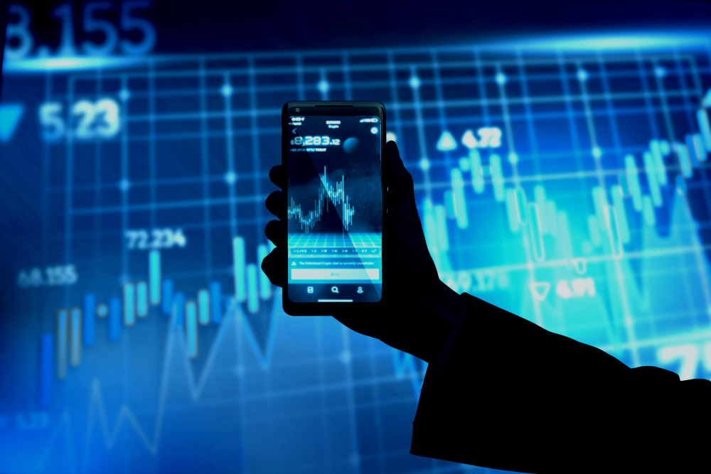 Hånd som holder oppe en telefon og trader på Bitcoin